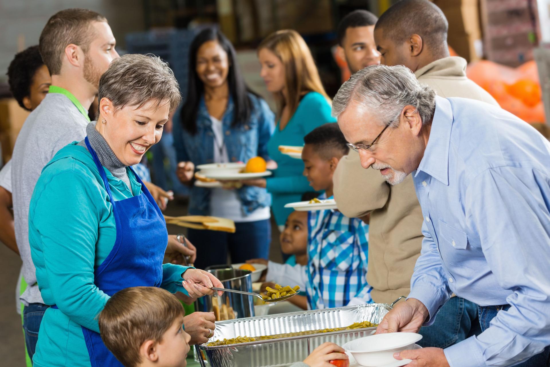Grandmother and young boy volunteering at food bank soup kitchen