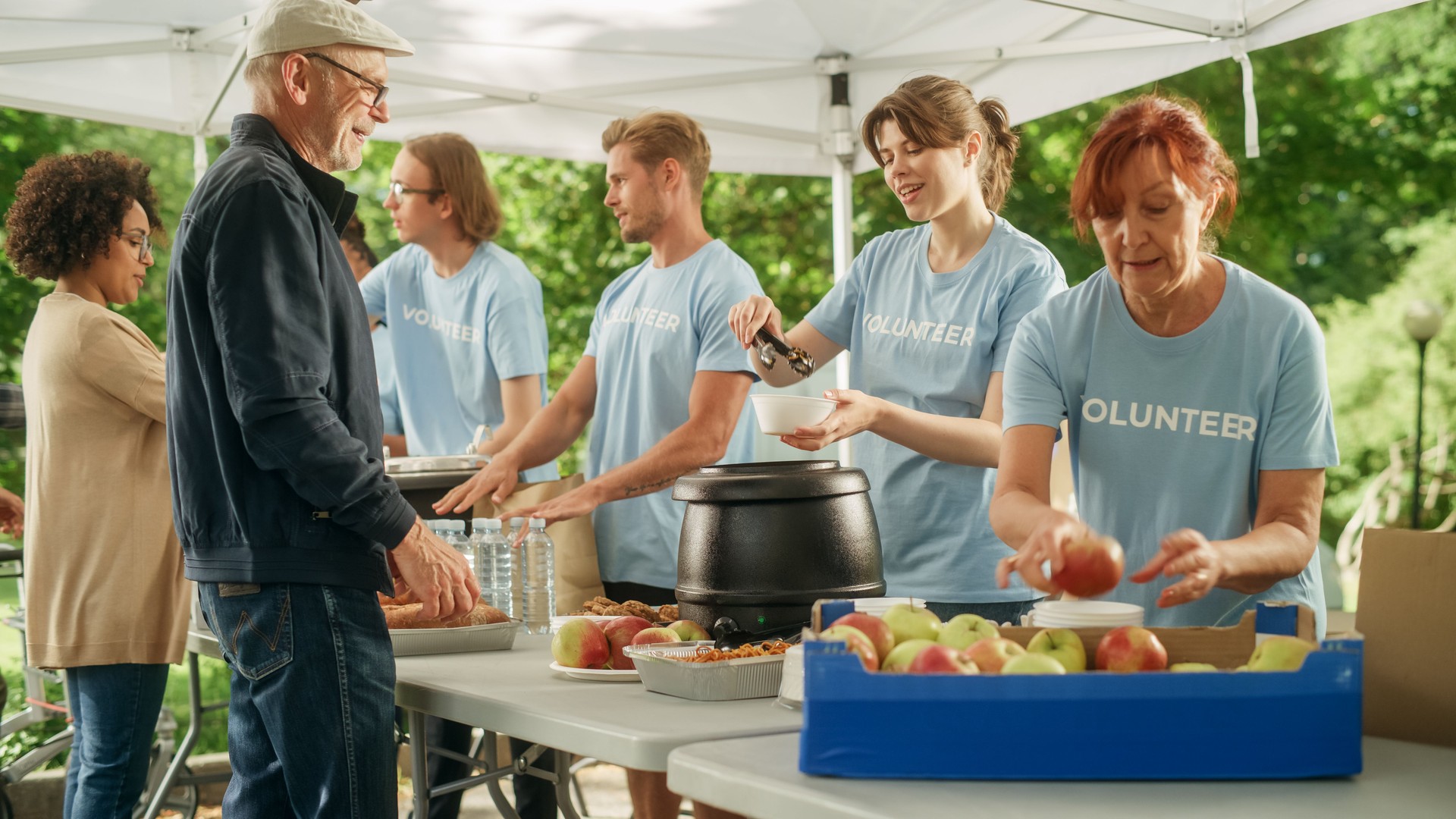 The Concept of Giving: Homeless People Reach Out To Free Volunteer Meals from Multiethnic Team of Volunteers. Humanitarian Aid Charity Workers Serve Meals to People in Need.